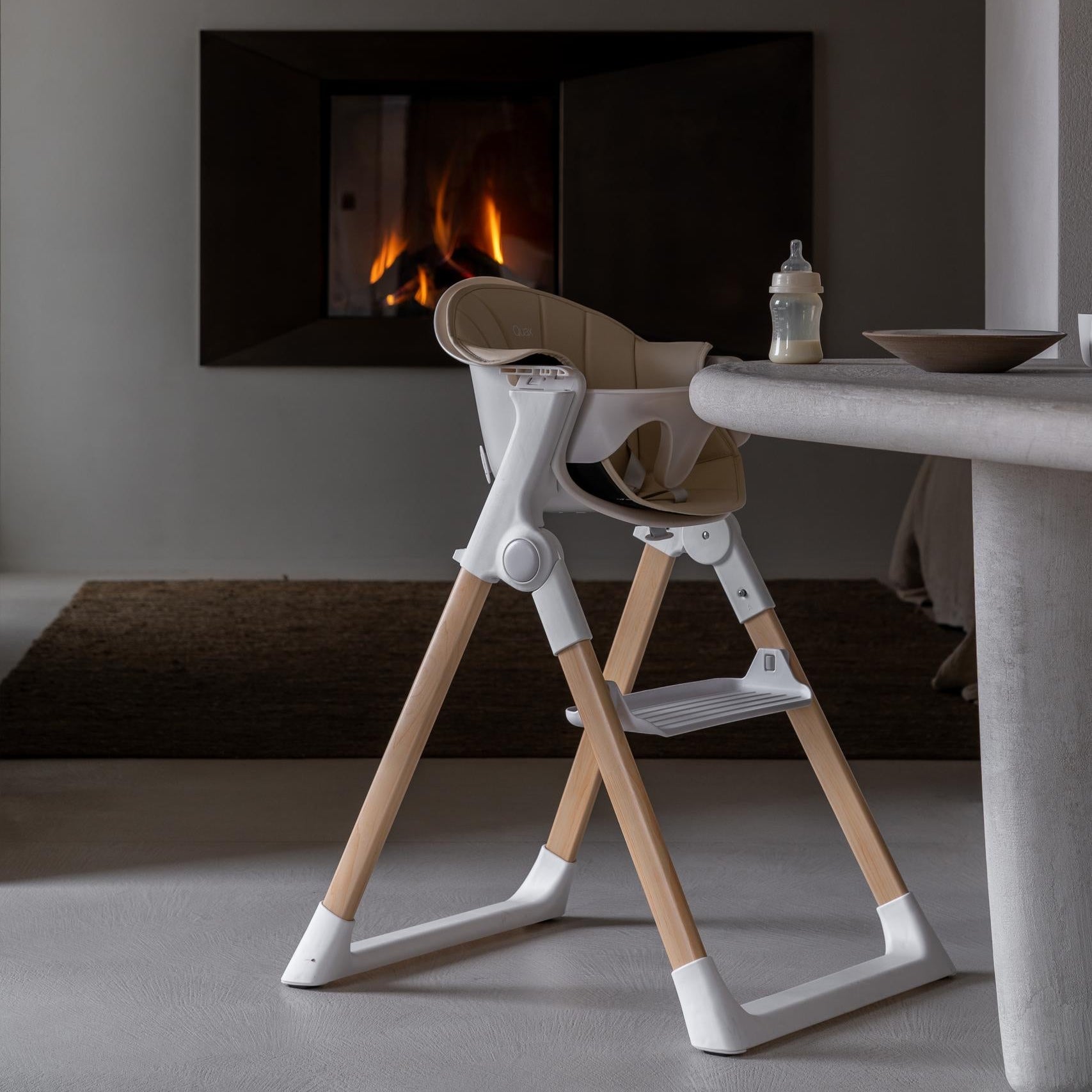Wooden high chair in a modern room with a fireplace.