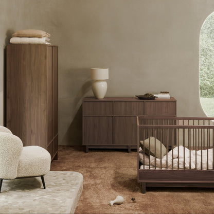 Nursery room with wooden furniture and a crib.