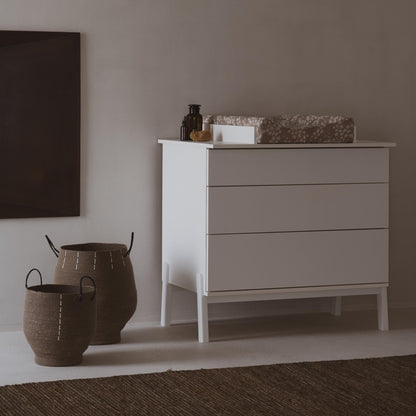 White dresser with decorative items against a plain wall