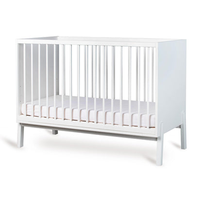 Cream crib with a white mattress on a white background