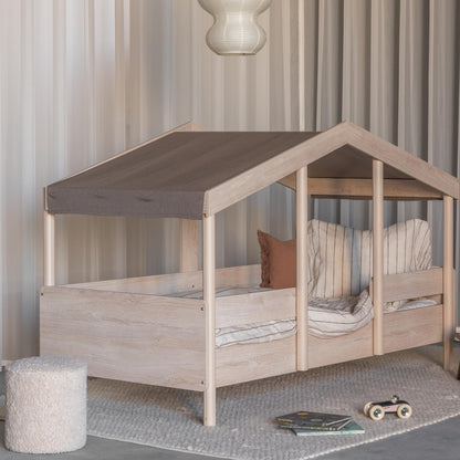 Children's montessori house-shaped bed with wooden frame and brown roof in a room setting.