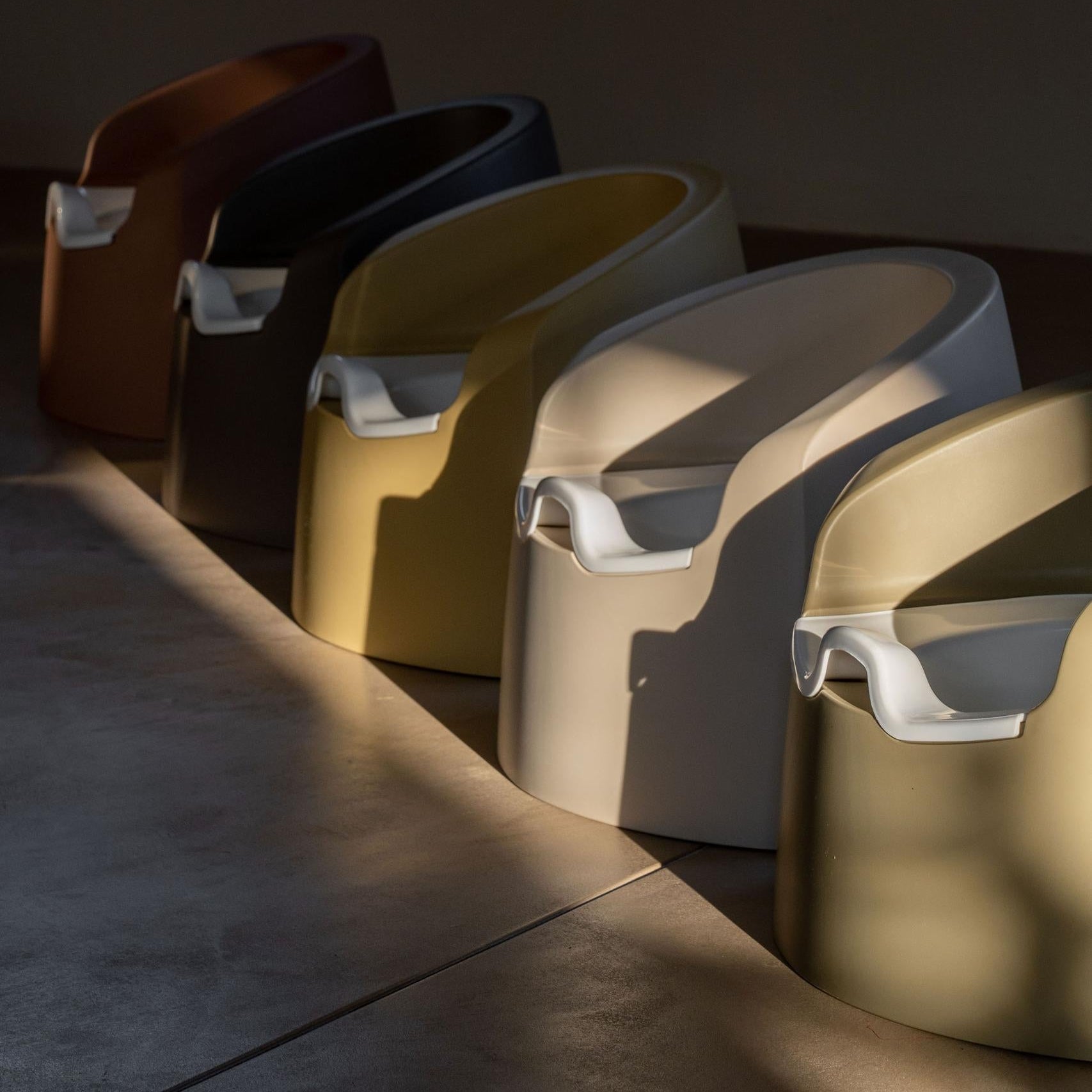 Row of modern stools with different colors on a dark floor.