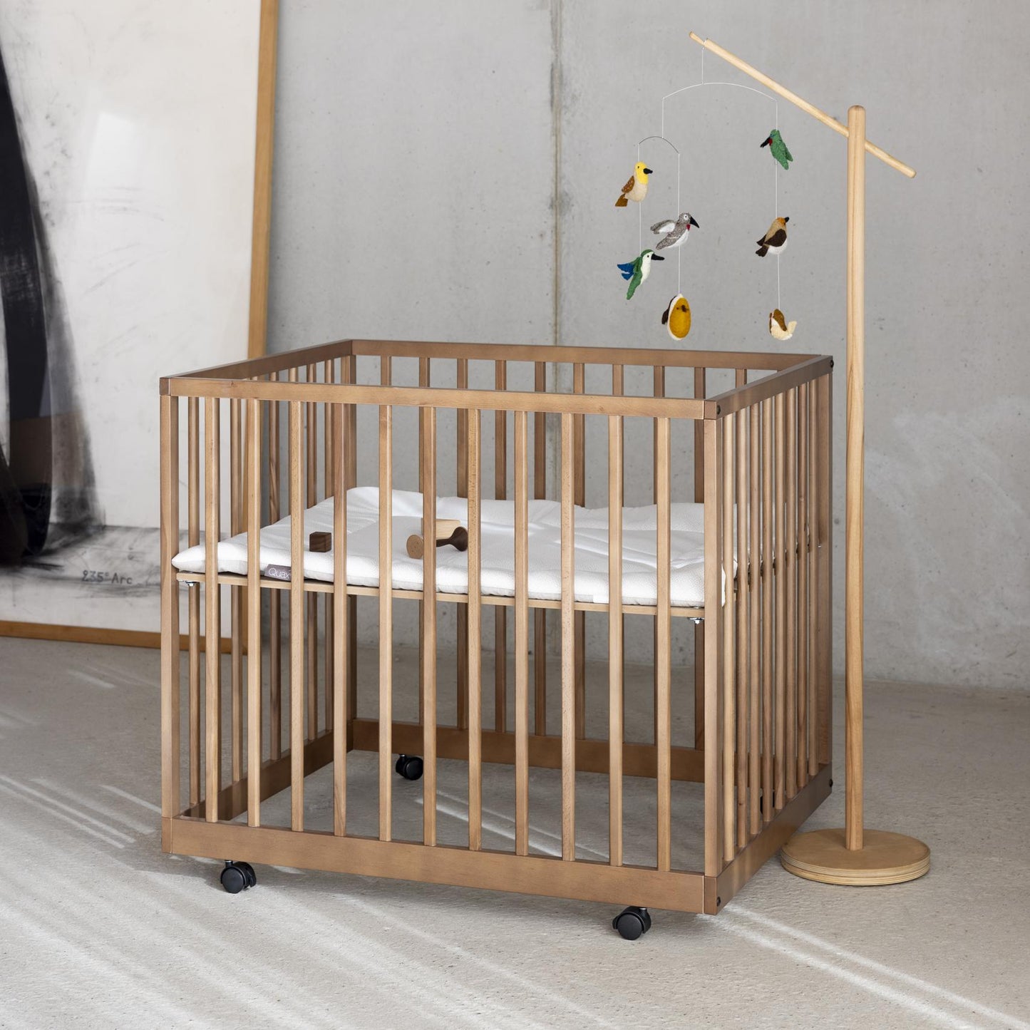 Wooden crib with a baby mobile in a minimalistic room.