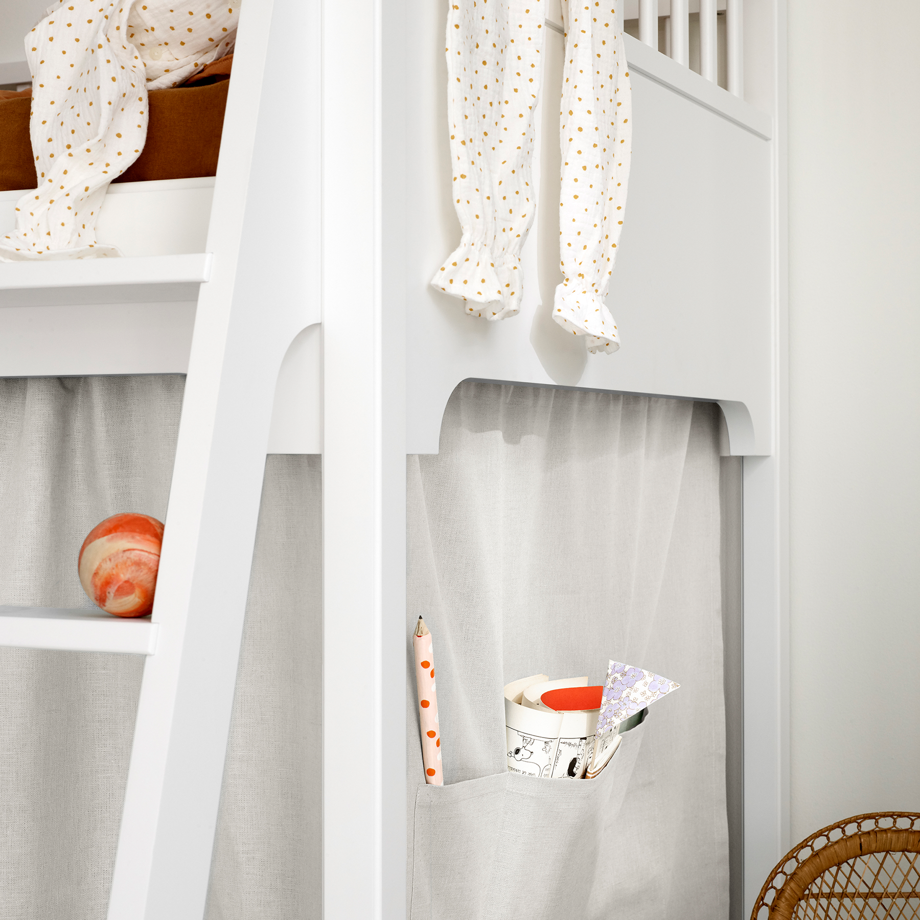 White loft bed with curtains and a small table with items on it.