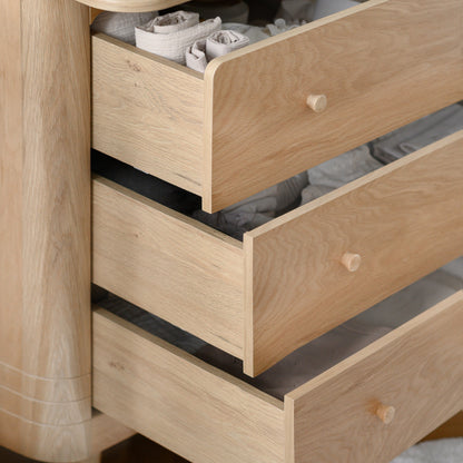 Wooden dresser with open drawers containing baby items on a neutral background