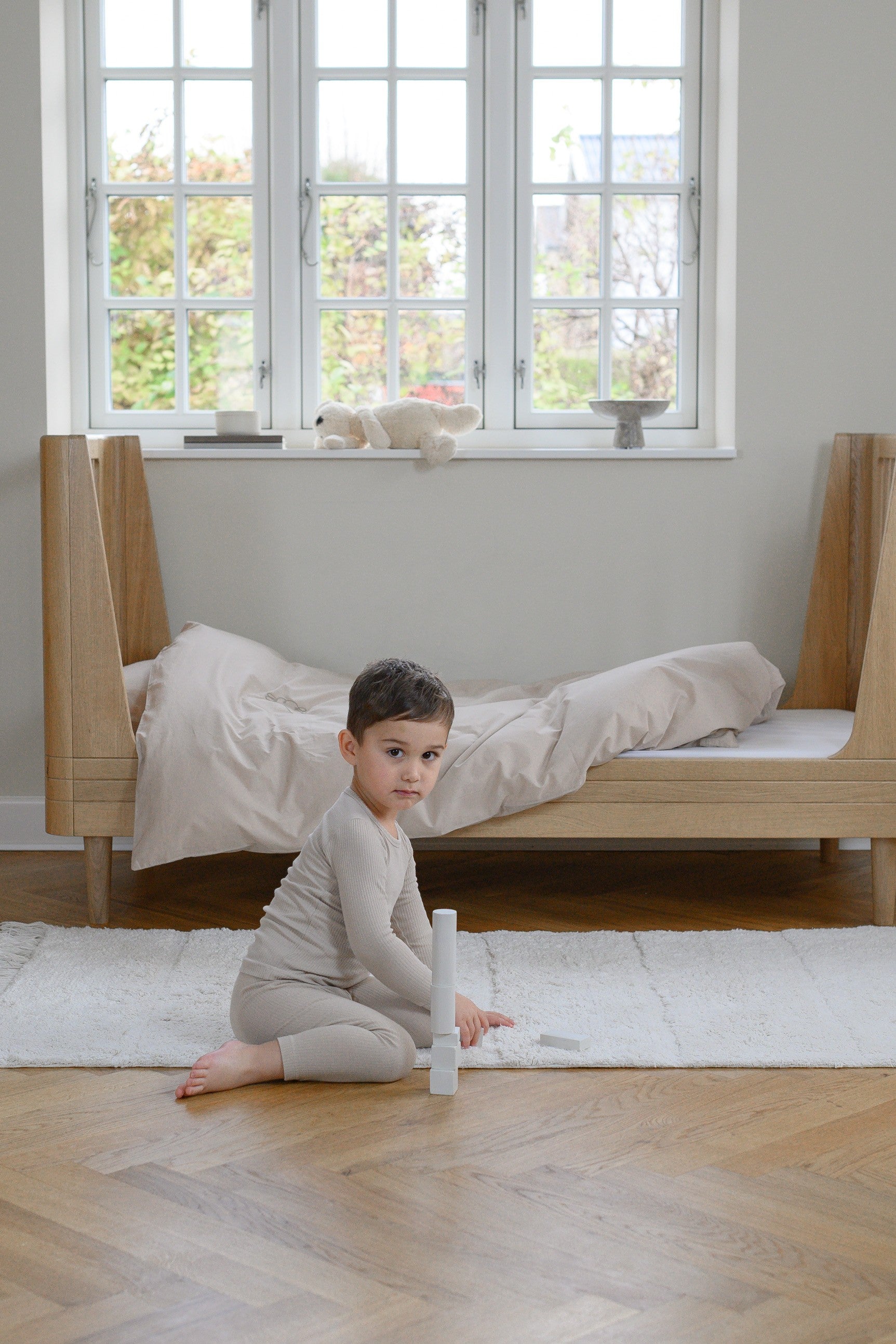 We are Bitte Toddle bed in Oak, with boy playing on the floor- by MK Kids Lifestyle-UK