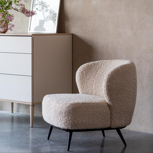 Beige teddy armchair and cabinet against a textured wall with a framed picture.