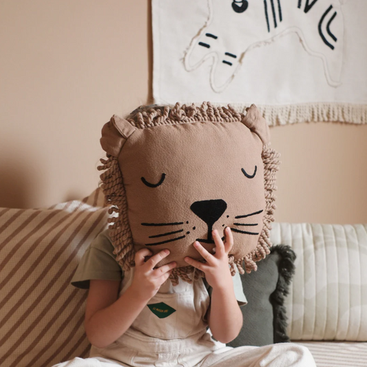 Child playing with a lion-shaped pillow in a cozy room.