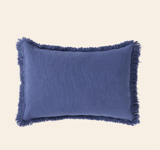 Blue pillow with frayed edges on a beige background