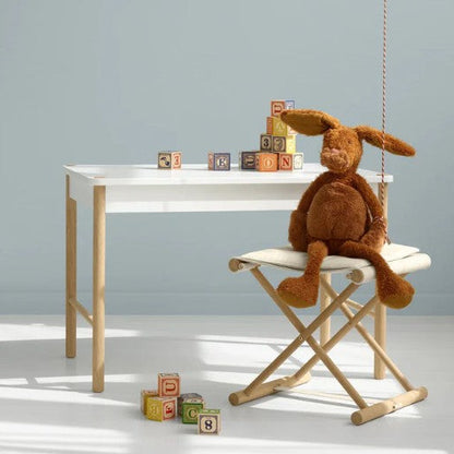 Children's play area with a white table, wooden chair, and colorful blocks against a light gray wall.