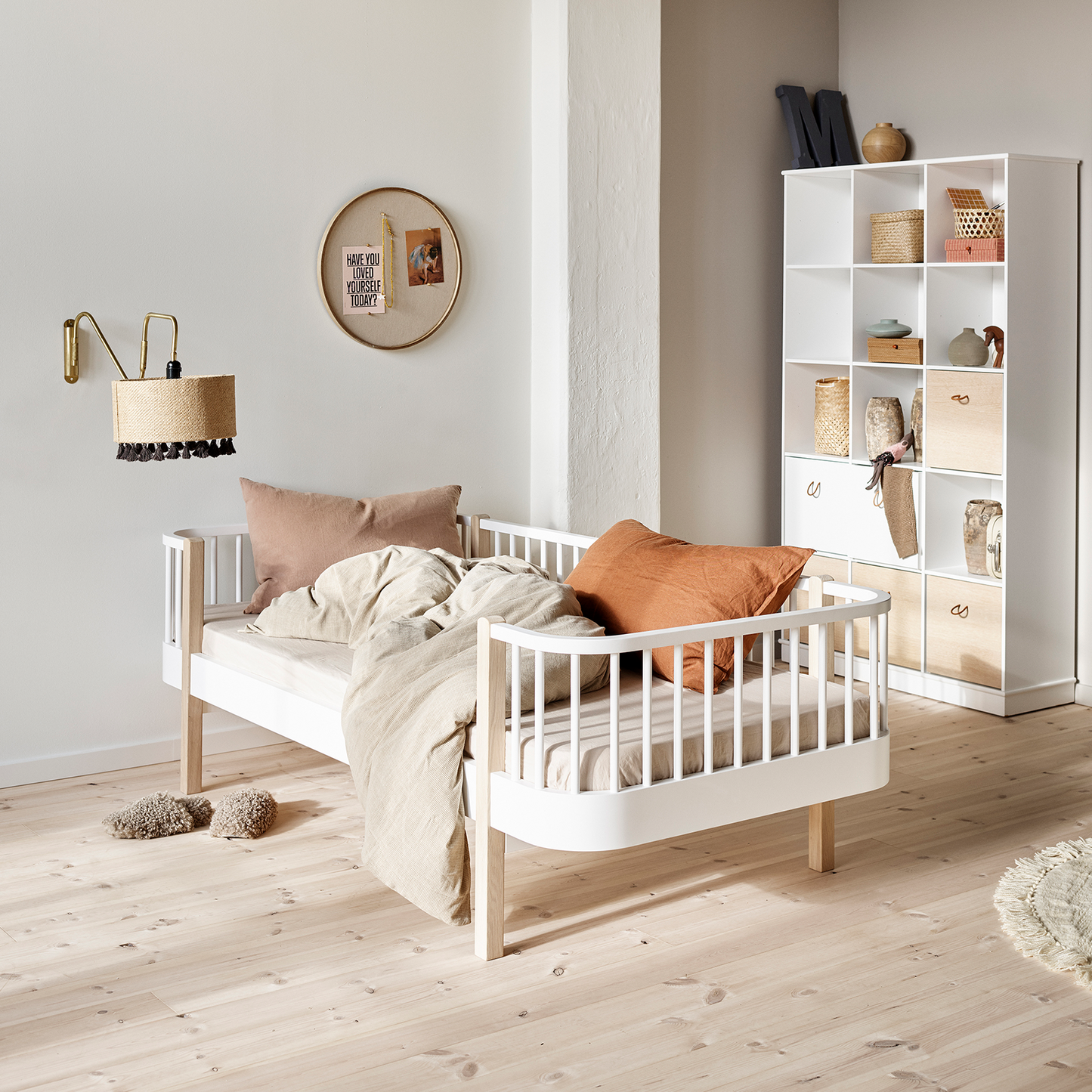 Children's bedroom with a white crib, pillows, and a bookshelf.